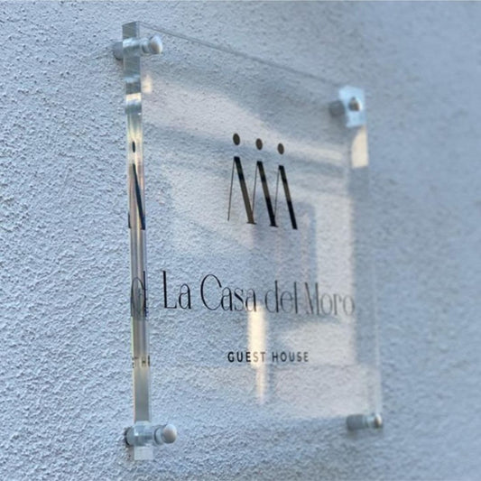 Targa in plexiglass trasparente con logo e distanziatori in metallo all'ingresso di un'attività